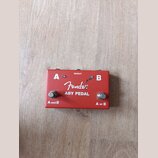Červený kovový efekt pedál s nápisy A a B v horních rozích. Uprostřed je bílé logo Fender® a pod ním text ABY PEDAL. V horní části je označení IN/OUT…