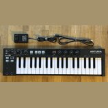 Černý MIDI kontrolér s 37 klávesami. Na levé straně je nápis KEYSTEP 37 controller & sequencer a vpravo logo ARTURIA s doplňkem The sound explorers.…