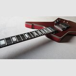 Elektrokytara s tmavě červeným lakem a bílým lemováním kolem korpusu. Hmatník je tmavý s velkými blokovými vložkami. Nástroj má dva humbuckery, dva o…