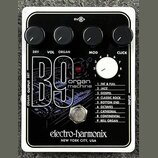 Kytarový efekt v bílém rámečku s černým povrchem. Na zařízení je nápis B9 organ machine a značka electro-harmonix NEW YORK CITY, USA. Obsahuje čtyři…