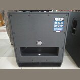 Černý aktivní subwoofer s matným povrchem. V pravém horním rohu je nalepený štítek s nápisy DXS18, 18" Powered Subwoofer a DSP. Uprostřed přední stra…
