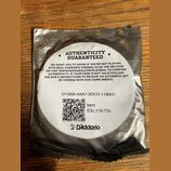 Kruhová bílá nálepka s černým textem umístěná na stříbrném obalu. Na nálepce je nápis AUTHENTICITY GUARANTEED, text s instrukcemi k ověření pravosti…