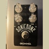 Černý kytarový efekt s čtyřmi průhlednými plastovými knoflíky. Na spodní části je bílý nápis SONICBONE DISTORTION a pod ním značka GOKKO. Nad knoflík…