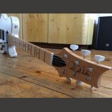 Elektrická kytara s přírodním dřevěným povrchem krku a hlavy. Na hlavě je černý nápis Paul Reed Smith® a na hmatníku jsou viditelné vložky ve tvaru p…