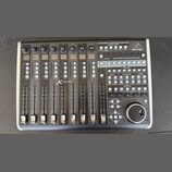 Černá kontrolní plocha s nápisem UNIVERSAL CONTROL SURFACE ENCOVER ROSSIGN a logem behringer. Zařízení obsahuje osm posuvníků, řadu tlačítek s různým…