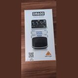 Fotografie znázorňuje krabici od efekt pedálu. Na krabici je zobrazen přístroj s nápisy DR600 DIGITAL REVERB a logo behringer. Na obrázku pedálu jsou…