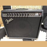 Černý kytarový kombozesilovač s textilní maskou a stříbrným logem Fender. Na horním ovládacím panelu je nápis FM 65R a FENDER MUSICAL INSTRUMENTS. Pa…