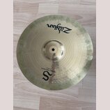 Kruhová mosazná činely s viditelným broušením povrchu. Na horní části je černý nápis Zildjian a ve spodní části velké písmeno S s dopisem MEDIUM THIN…
