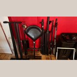 Sestava černého hudebního příslušenší z kovových materiálů. Na fotografii je vidět skládací notový stojan, židlička s černým polstrováním, několik ty…