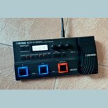 Černý kytarový procesor s nápisem BOSS GT-1 GUITAR EFFECTS PROCESSOR. Zařízení má digitální displej, na kterém je text TERA ECHO LEAD a další ovládac…