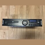 Černý rackový MP3 přehrávač s nápisy Numark na levém a pravém okraji. Na předním panelu je uvedený model MP 103 USB a nápis PROFESSIONAL MP3 MEDIA PL…