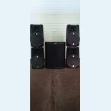 Pět černých reproduktorů v plastových skříních. Uprostřed stojí jeden velký subwoofer s nápisem ALTO, po stranách jsou dva sloupce dvou menších repro…