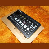 Černý kompaktní sampler Roland SP-S s numerickou klávesou od 1 do 6 a řadou ovládacích tlačítek. Na horní části je logo Roland a označení SP-S, dále…
