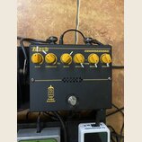 Černý efekt pedál s nápisy Markbass a COMPRESSORE. Na horní části jsou šest žlutých otočných ovladačů s popisky GAIN, THRESHOLD, RATIO, ATTACK, RELEA…