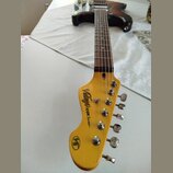 Elektrická kytara s hnědým gradientem těla a světlým dřevěným krčkem. Na hlavě je nápis „Vintage ICON Series™“ a v dolní části logo „V6“. Nástroj vyk…