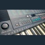 Detailní pohled na ovládací panel a klávesy elektronického klavíru. Na panelu jsou nápisy OVERALL CONTROLL, TEMPO, TRANSPOSE a SPLIT POINT CHANGE. V…
