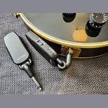 Dvě černé bezdrátové vysílače/přijímače s kovovými jack konektory. Na levém zařízení je nápis RECEIVER, na pravém jsou nápisy POWER PAIR, CHARGE ID a…