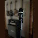 Černý dynamický mikrofon s mřížkou a bílým prstenem v horní části. Na těle je viditelné logo AKG a nápis D 5. Povrch mikrofonu je matný a v dobrém st…
