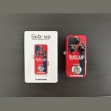 Fotografie zobrazuje červený efekt pedál a jeho originální krabici. Na pedálu i na krabici je bílý nápis Subnup MINI OCTAVER a logo tc electronic. Pe…