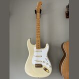 Bílá elektrická kytara s jasným dřevěným hmatníkem a bílým pickguardem. Na hlavě krku je viditelné logo Fender. Nástroj má tři snímače s bílými krytk…