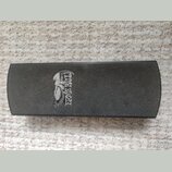 Černý obdélníkový předmět s texturovaným povrchem. Na levé straně je bílé logo s vyobrazením orla a nápisem ERNIE BALL. Povrch je v dobrém stavu bez…