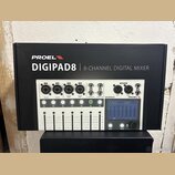 Fotografie znázorňuje krabici s digitálním mixážním pultem. Na krabici je nápis PROEL DIGIPAD8 | 8-CHANNEL DIGITAL MIXER. Zobrazený přístroj je bílý…