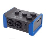 Černý audio interface s modrými ochrannými rámy v rozích. Na horní straně jsou čtyři ovládací knoflíky a nápisy ZOOM, AMS-24 a AUDIO I/F for MUSIC &…