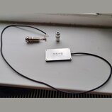 Na fotografii je stříbrný obdélníkový snímač s nápisem KRIVO PICK-UPS. K němu je připojen černý kabel, který končí kovovým jack konektorem. Vedle sní…