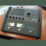 Černý kytarový procesor s nápisem FM3 MARK II AMP MODELER/FX PROCESSOR. Zařízení má velký displej, ovládací knoflíky a tlačítka s popisky HOME, EDIT,…
