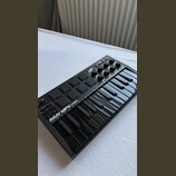 Černý kompaktní MIDI kontrolér s klávesnicí a padovými polštáři. Na přístroji je bílý nápis AKAI PROFESSIONAL MPK mini. Povrch je v dobrém stavu, bez…