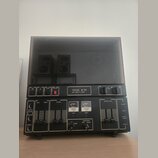 Černý cívkový magnetofon s průhledným plastovým krytem. Na předním panelu je nápis TESLA B 113 a pod ním HIGH FIDELITY STEREO. Zařízení obsahuje něko…
