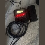 Černý multiefektový procesor s nápisem A1X FOUR ZOOM Multi-Effect Processor. Zařízení má podsvícený displej a řadu červeně svítících LED diod nad čís…