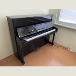 Černý digitální piano v şeklinde konzolového pianina s glossy povrchem. Na přihradě nad klávesnicí je bílý nápis "Pitmüller". Nástroj má standardní k…