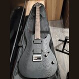 Černá elektrická kytara s výraznou strukturou dřeva na těle a hneděm hmatníkem. Nástroj má dva humbuckery, dva ovladače a stříbrný most s pružinami.…