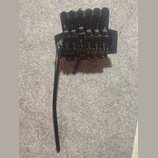 Černý kobylkový systém pro elektrickou kytaru s pákou. Na pravé straně je vidět nápis „Ibanez EDGE“. Povrch vykazuje známky opotřebení a oxidace v ob…