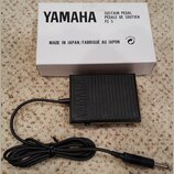 Černý sustain pedál značky YAMAHA s texturovaným povrchem. Vedle něj je bílá krabice s nápisy YAMAHA, SUSTAIN PEDAL PÉDALE DE SOUTIEN FC 5 a MADE IN…