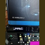 Fotografie zobrazuje bezdrátový přijímač značky SENNHEISER s nápisem XS WIRELESS 2 a digitálním displejem, na kterém je vidět hodnota 548.250 MHz a d…