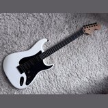 Bílá elektrická kytara s černým pickguardem a hmatníkem z tmavého dřeva. Na hlavě je viditelné logo „Fender“ a nápis „STRATOCASTER“. Nástroj má jeden…