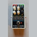 Kytarový efekt pedál v bílém kovovém rámu s černým předním panelem. Na panelu jsou nápisy BATTALION, bass pre/drive a značka electro-harmonix NEW YOR…