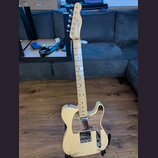 Světle žlutá elektrická kytara s tvarem typu Telecaster a javorovým hmatníkem. Na hlavě je vidět nápis "Fender" a pod ním modelové označení "TELECAST…