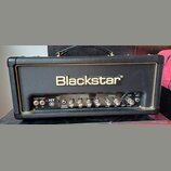 Černý kytarový kombozesilovač s logem Blackstar na předním panelu. Na ovládacím panelu je nápis HT 5 a sekce s popisky POWER, STANDBY, CABINET, EMULA…