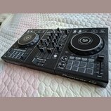 Černý DJ kontrolér s dvěma jog-koly a centrálním mixážním sekcí. Na přístroji jsou viditelný nápisy Pioneer DJ a rekordbox. Povrch je v dobrém stavu,…