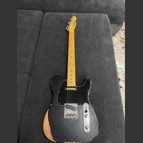 Elektrická kytara typu Telecaster s černým trupem a světle hnědým javorovým hmatníkem. Na hlavě je viditelné logo "Hagström". Trup vykazuje výrazné o…