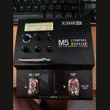 Černý efekt pedál s nápisy LINE 6 a M5 STOMPBOX MODELER. Pod názvem modelu jsou uvedeny kategorie DELAY | MOD | DISTORTION | FILTER | VERB. Displej z…