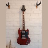 Elektrická kytara s červeným trupem v charakterickém tvaru SG a černým pickguardem. Na hlavě hmatníku je bílý nápis Gibson. Nástroj má dva humbuckery…
