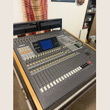 Šedý mixovací pult s nápisem YAMAHA a označením O2R. Obsahuje digitální displej, řadu posuvníků a zahlreiche ovládací tlačítka v bílé a žluté barvě.…