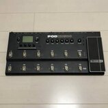 Černý kytarový procesor s řadou ovládacích tlačítek, otočných potenciometrů a displejem. Na horní části je bílý nápis POD HD500 a vpravo na výrazném…