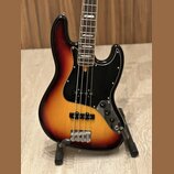 Elektrická basová kytara s korpusem v barevném přechodu od žluté přes oranžovou k červené a černé. Nástroj má černý pickguard, dva snímače a čtyři ov…