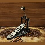 Fotografie znázorňuje černý bicí pedál s kovovou stálkou v stříbrné barvě. Na stálce je umístěno černé logo ve tvaru stylizovaného písmene B v oválu.…