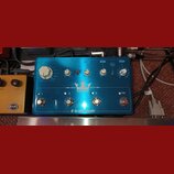 Modrý efekt pedál s nápisy TRIPLE FLASHBACK a tc electronic. Na horní části jsou čtyři bílé otočné ovladače a přepínače s popisky TAPE, TUBE, SPACE,…